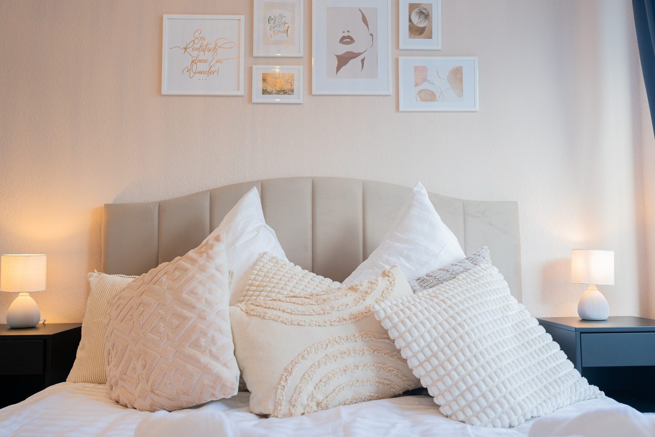 Schlafzimmer mit Doppelbett, Polsterkopfteil, Kissen und Nachttischlampen