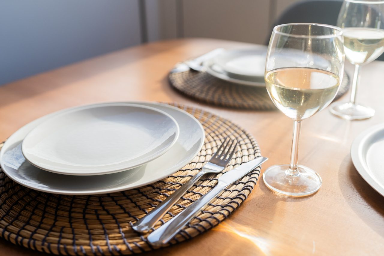 Gedeckter Tisch mit Tellern, Besteck und Weißweinglas