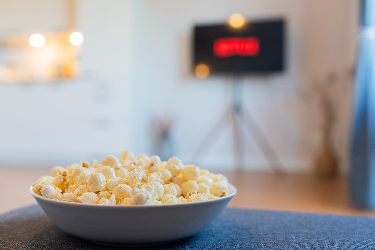 Schüssel mit Popcorn vor einem Fernseher mit Netflix