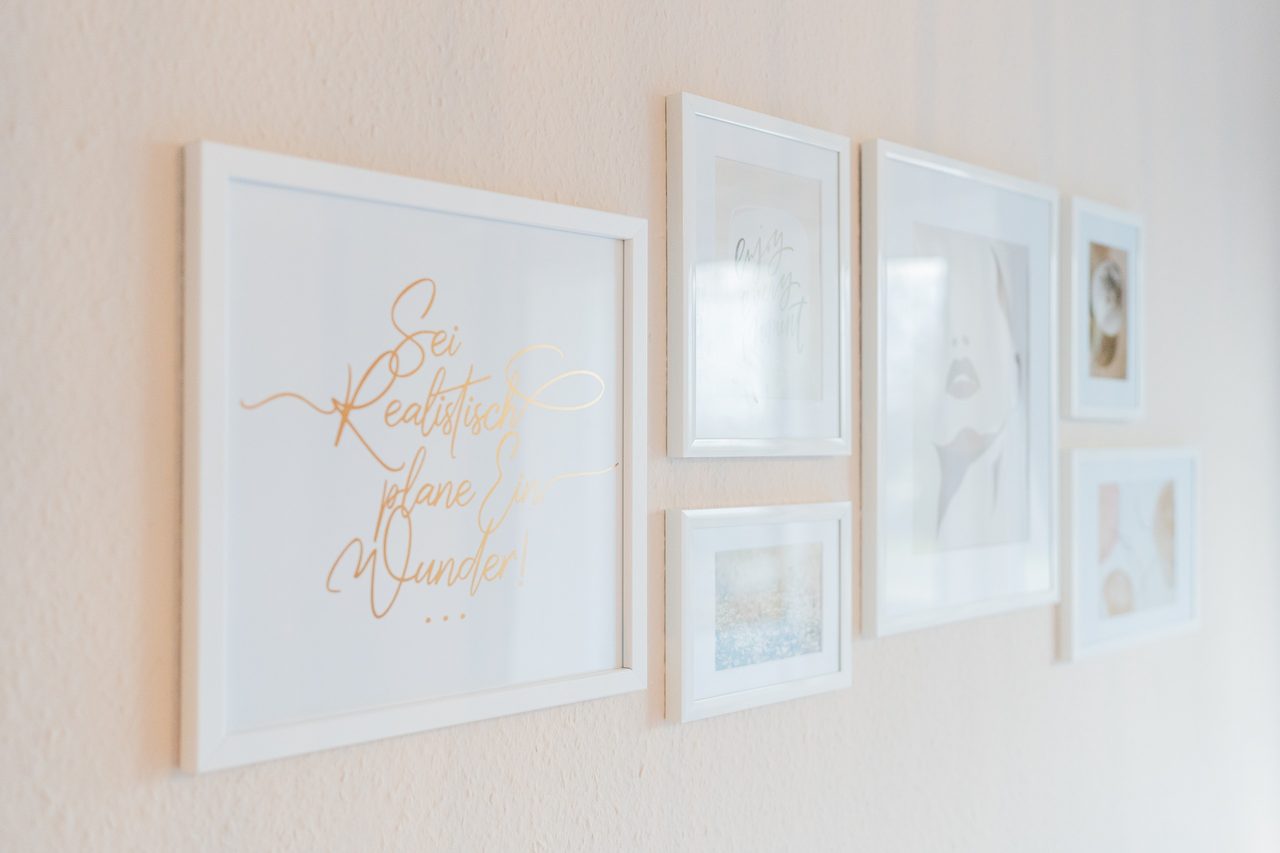 Bilderrahmen mit Schriftzug und Fotos an heller Wand