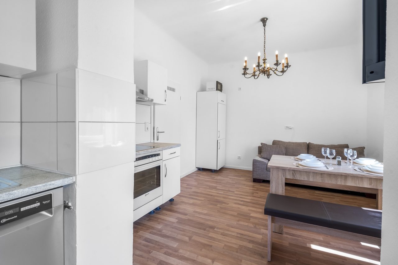 Wohnküche mit Küchenzeile, Kühlschrank, Esstisch und Sofa