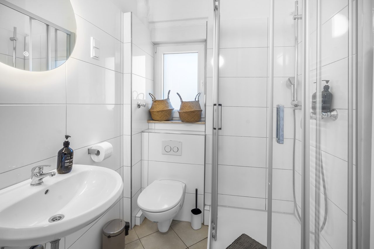 Badezimmer mit Waschbecken, Toilette und Dusche mit Glastür
