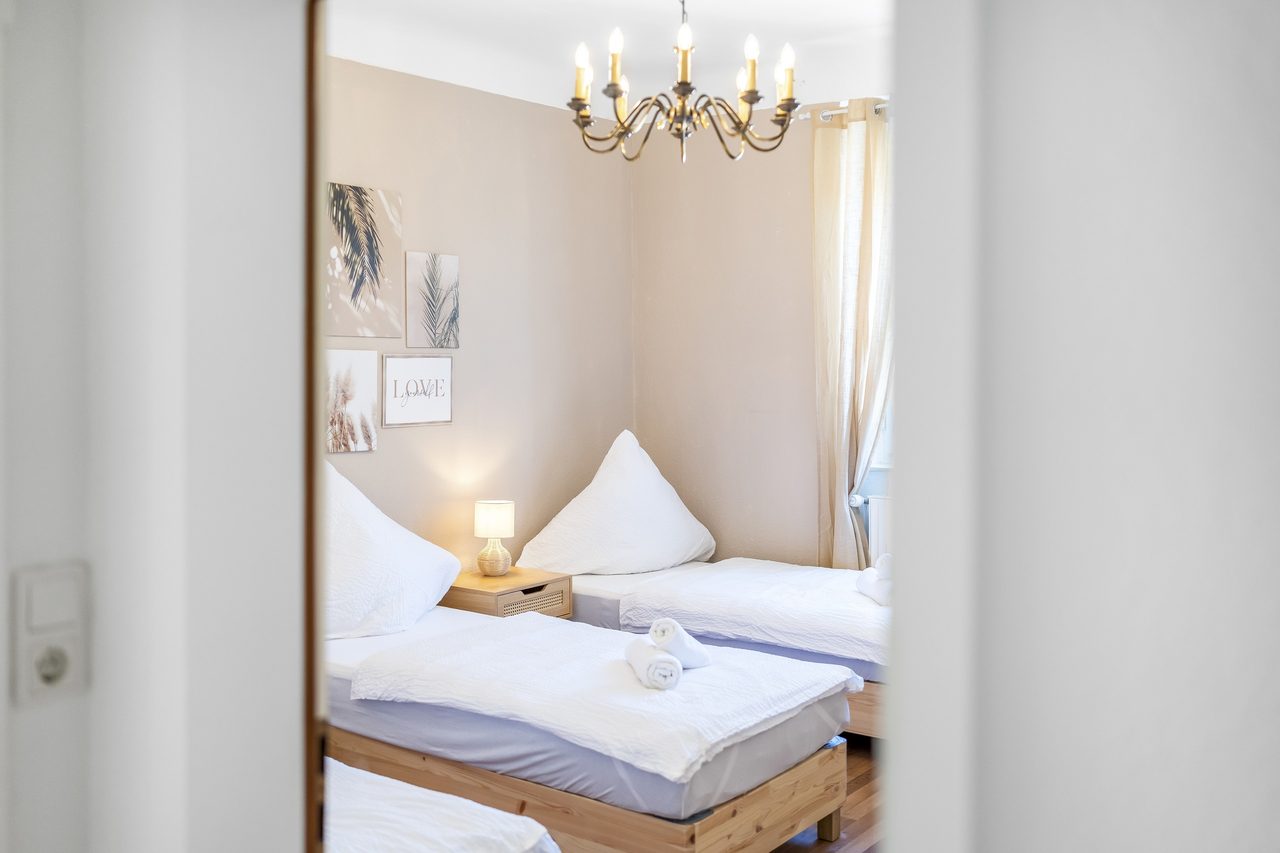 Blick durch die Tür in ein Schlafzimmer mit Einzelbetten und Kronleuchter