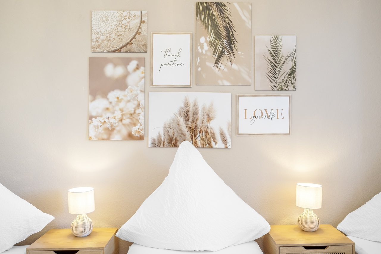 Schlafzimmer mit weißen Kissen, zwei Nachttischlampen und Bildercollage