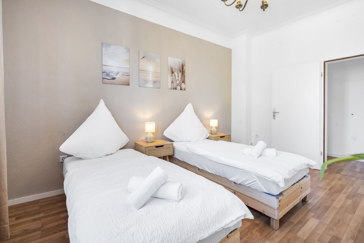 Schlafzimmer mit zwei Einzelbetten, Nachttischlampen und drei Wandbildern