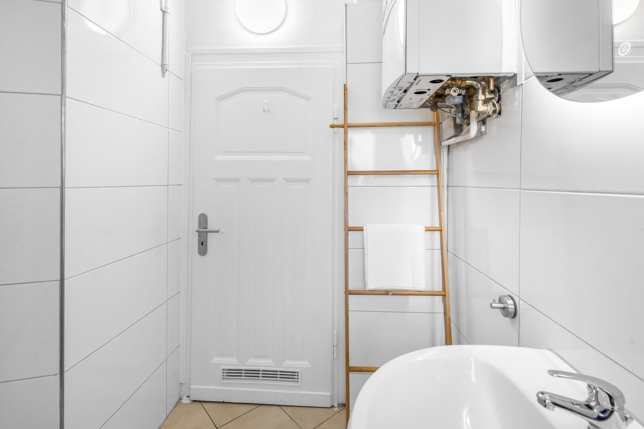 Badezimmer mit Tür, Handtuchleiter aus Holz und Waschbecken
