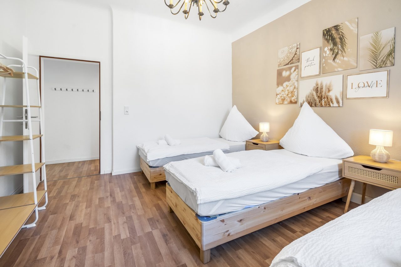 Schlafzimmer mit Einzelbetten, Kleiderregal und Bildercollage an der Wand