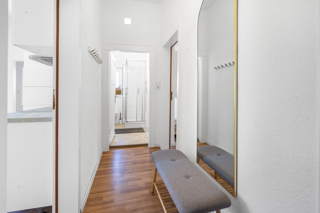 Flur mit Holzboden, Sitzbank und großem Bogenspiegel