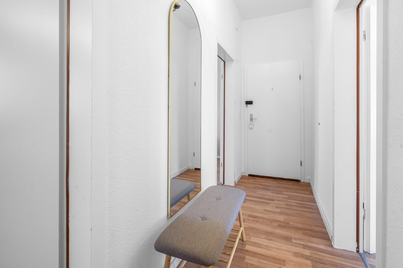 Flur mit Sitzbank, Bogenspiegel und Blick zur Wohnungstür