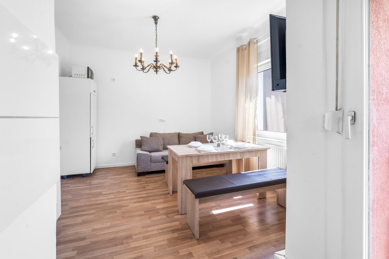 Wohnbereich mit Sofa, Esstisch mit Bank und Kronleuchter