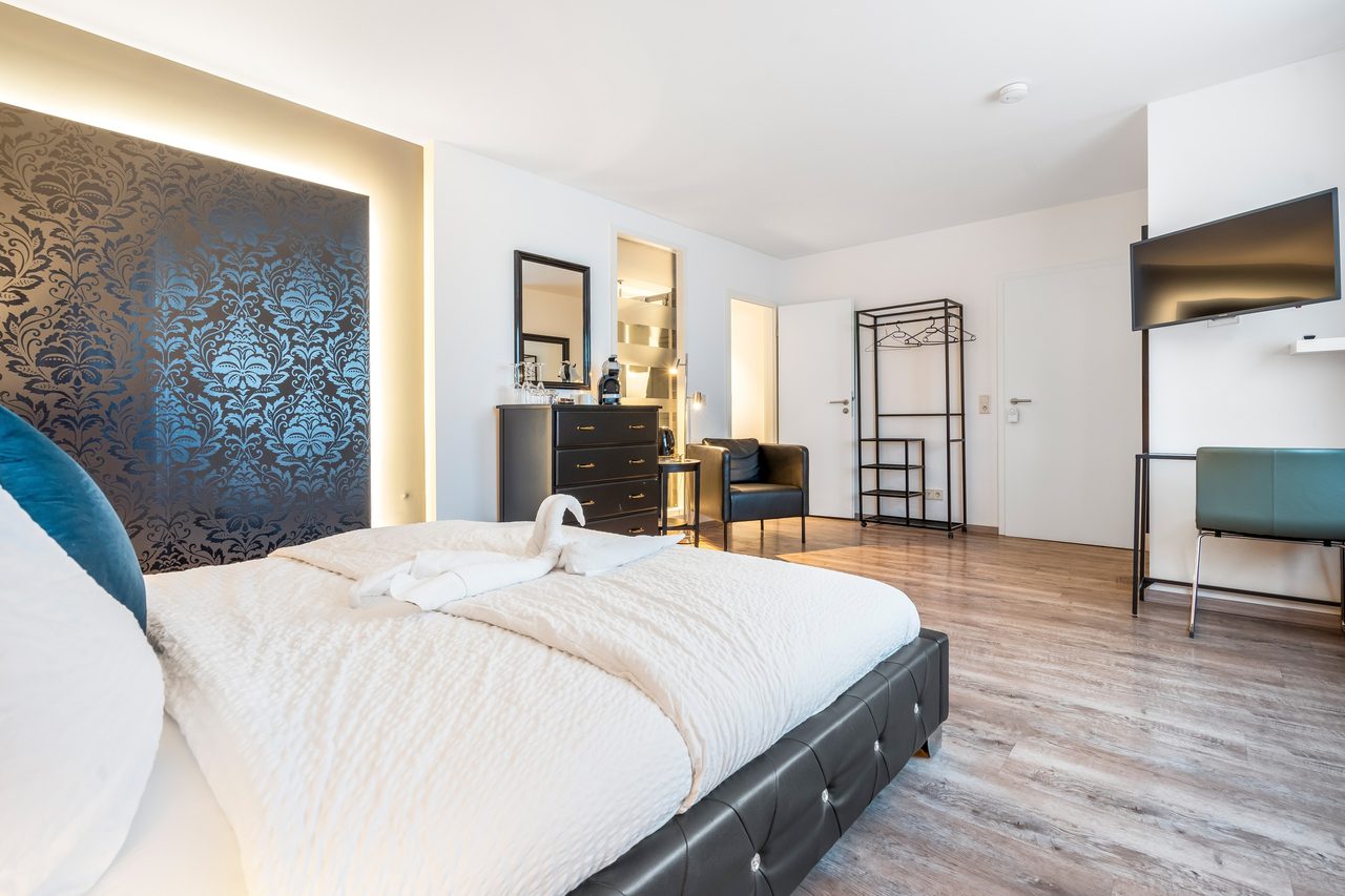 Schlafzimmer mit Doppelbett, gemusterter Wand und Wandfernseher