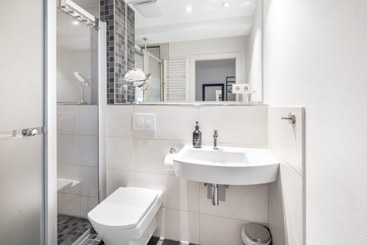 Badezimmer mit Waschbecken, Wand-WC und Spiegel