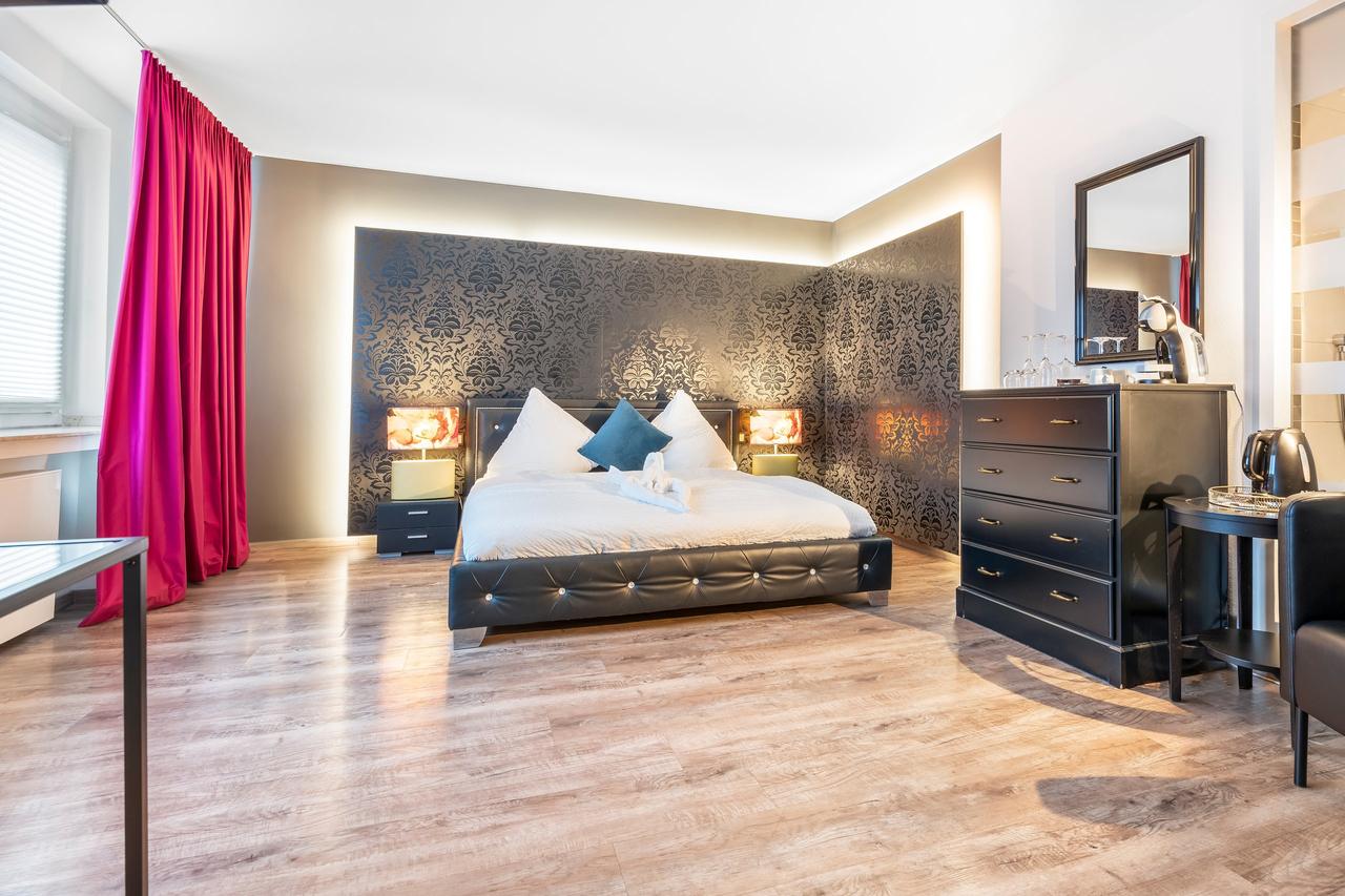 Schlafzimmer mit Doppelbett, Mustertapete und pinken Vorhängen