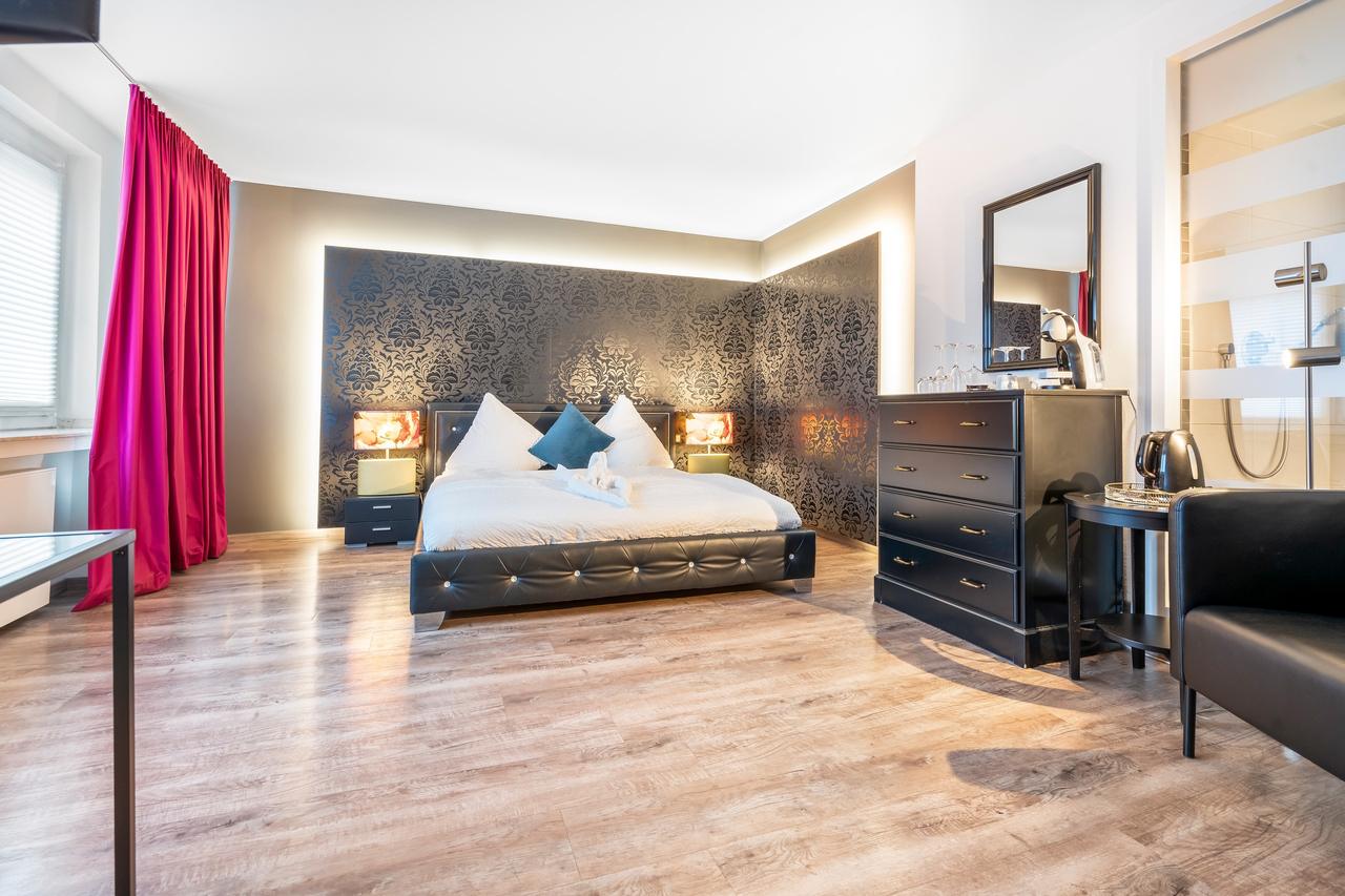 Schlafzimmer mit Doppelbett, schwarzer Kommode und beleuchteter Mustertapete