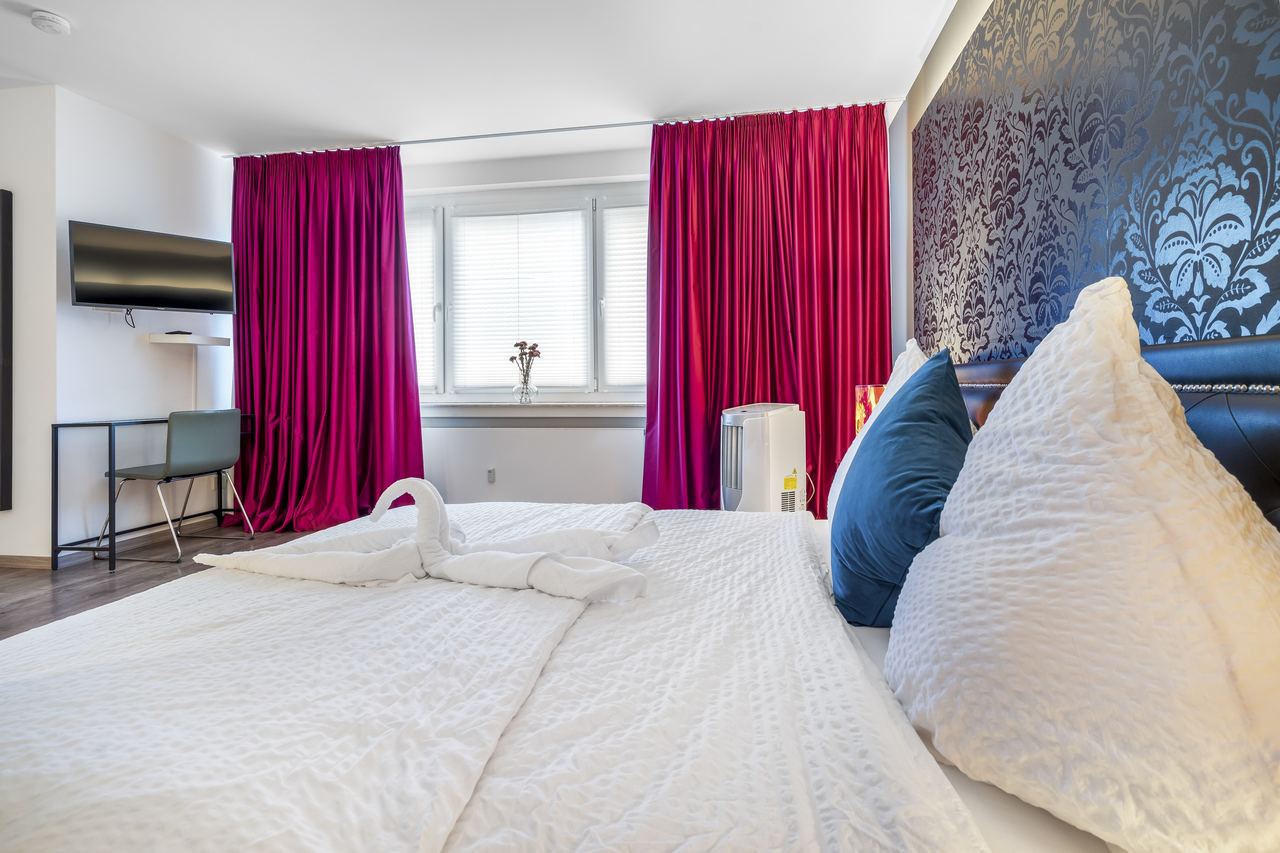 Bett mit Handtuchschwan, Kissen und Blick auf Fenster