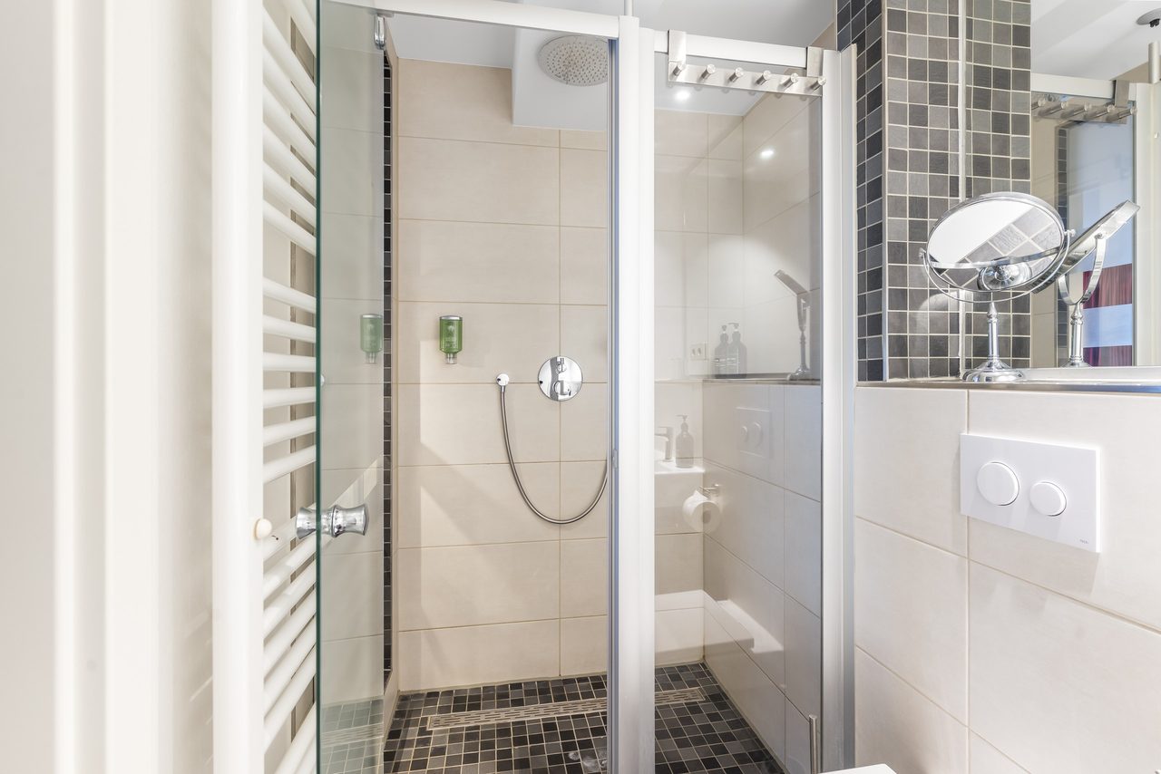 Badezimmer mit Dusche, Glastür und Kosmetikspiegel