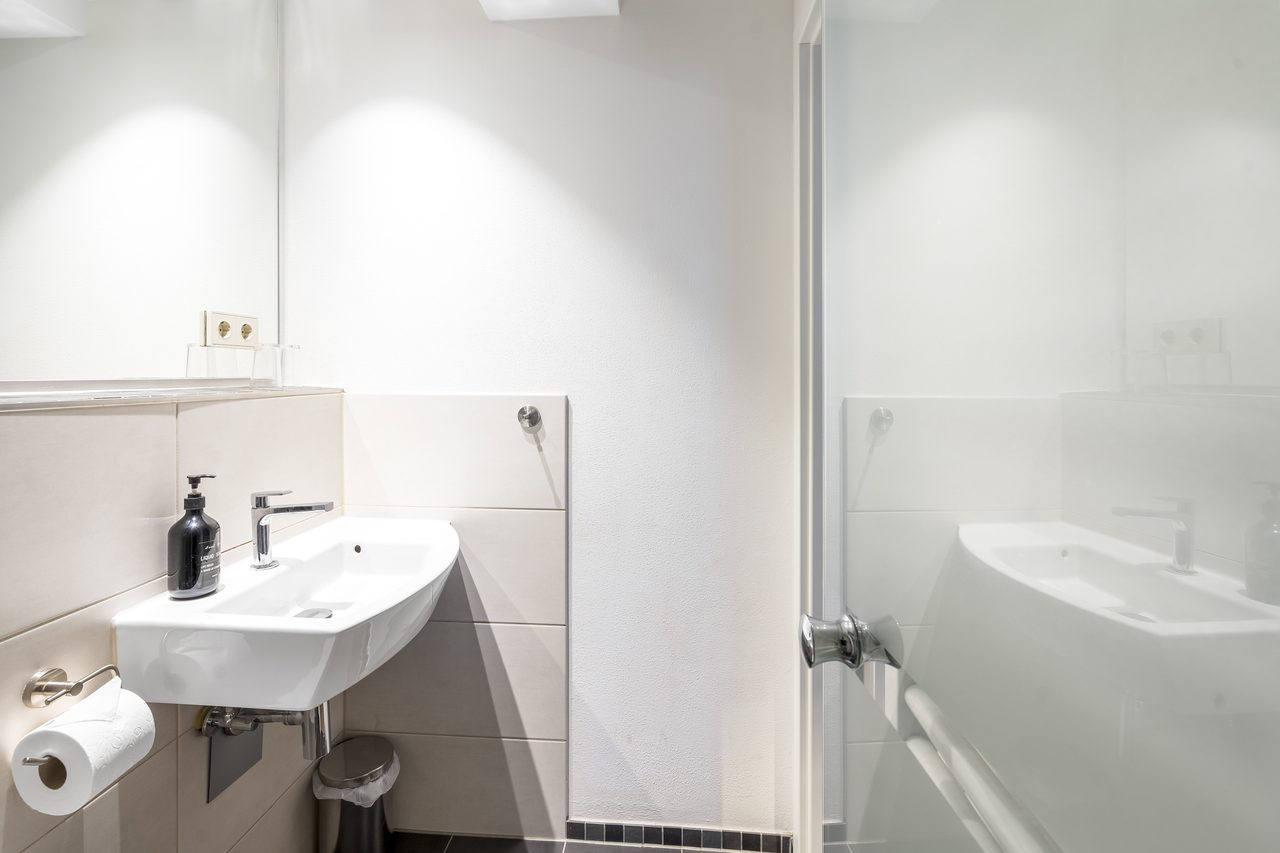 Badezimmer mit Waschbecken, Seifenspender und Toilettenpapierhalter