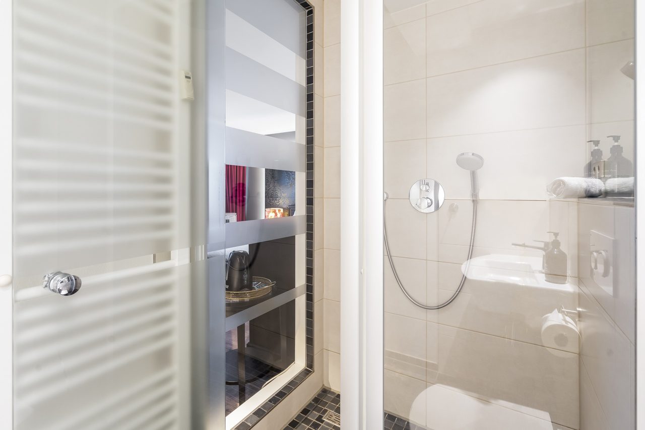 Badezimmer mit Handtuchheizkörper, Dusche und Waschbecken