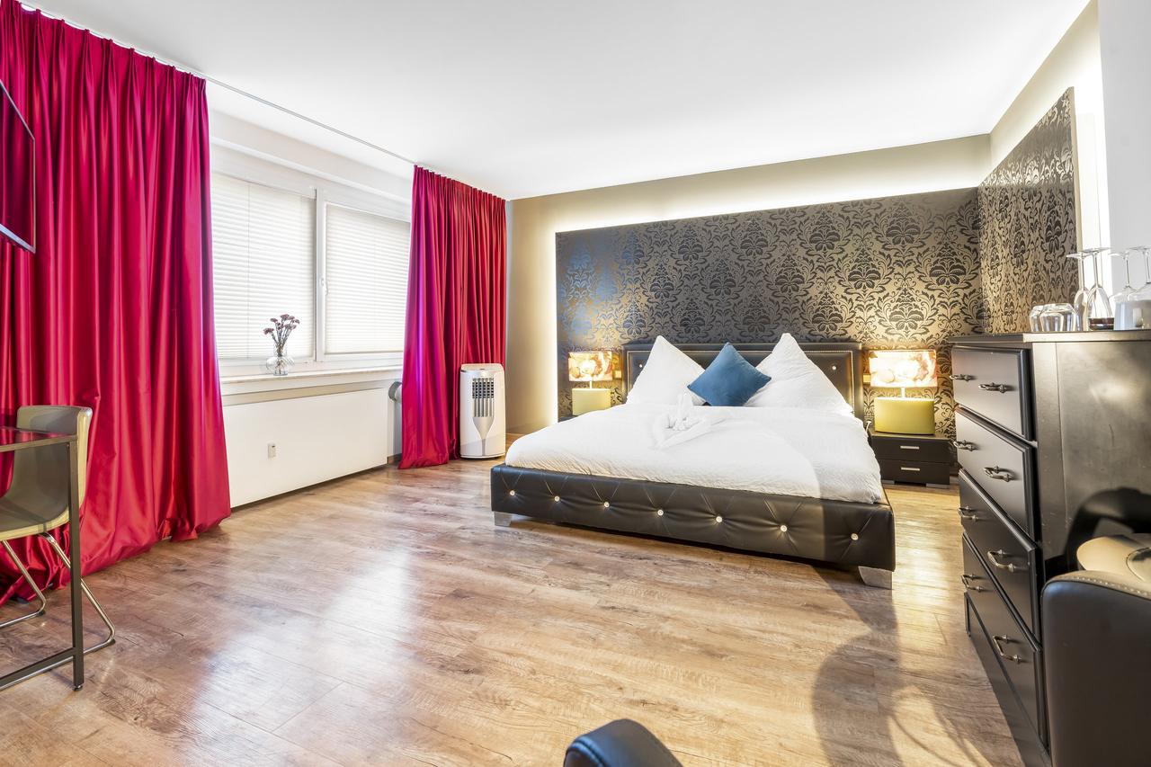 Schlafzimmer mit Doppelbett, schwarzer Kommode und pinken Vorhängen