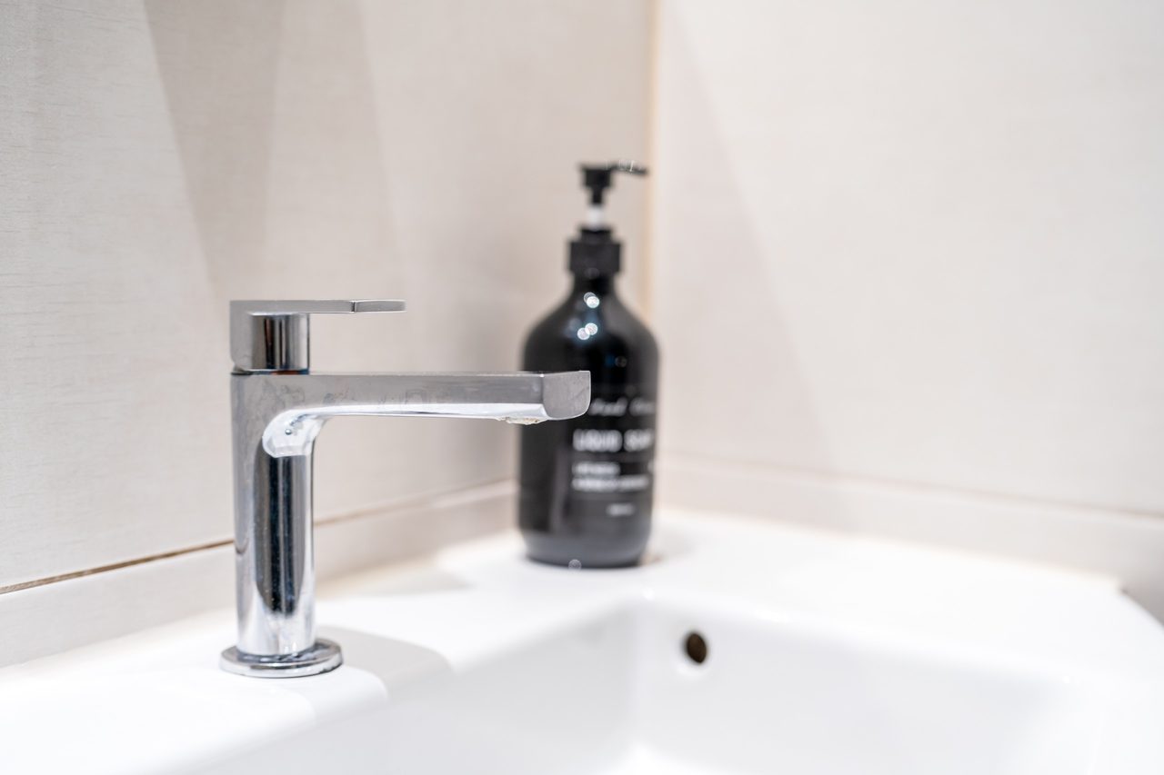 Waschbecken mit Chromarmatur und schwarzem Seifenspender