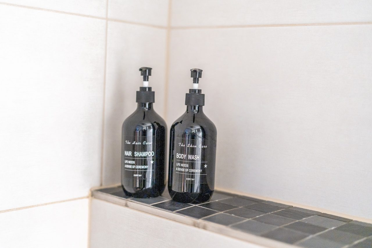 Zwei schwarze Flaschen mit Shampoo und Duschgel auf Ablage