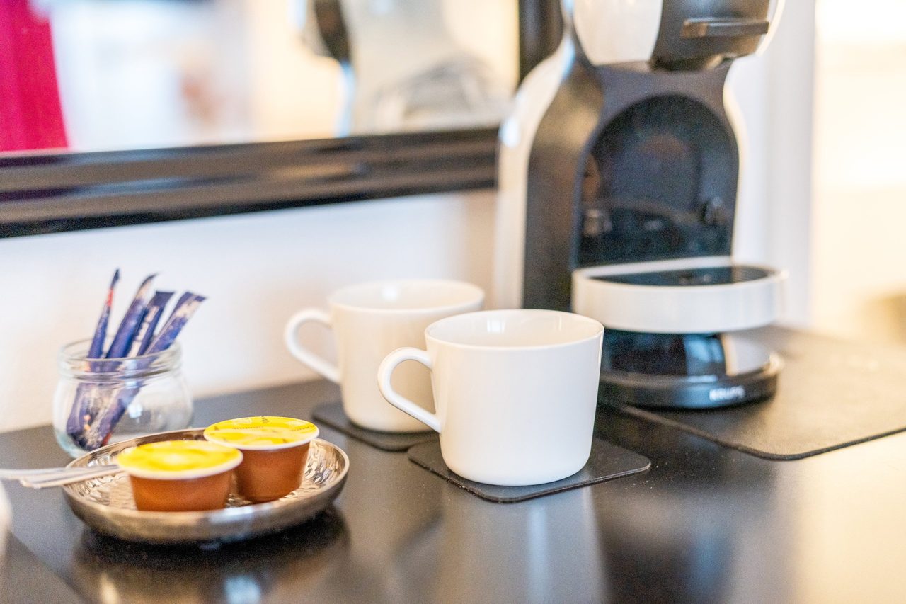 Kaffeekapselmaschine mit Tassen, Kapseln und Zuckersticks