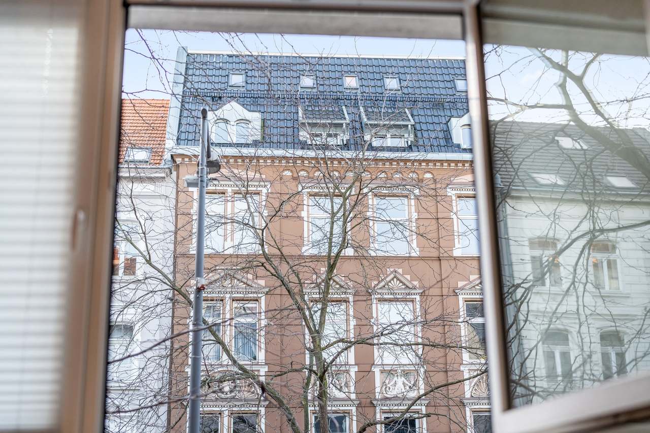 Blick durchs Fenster auf ein Backsteinhaus gegenüber