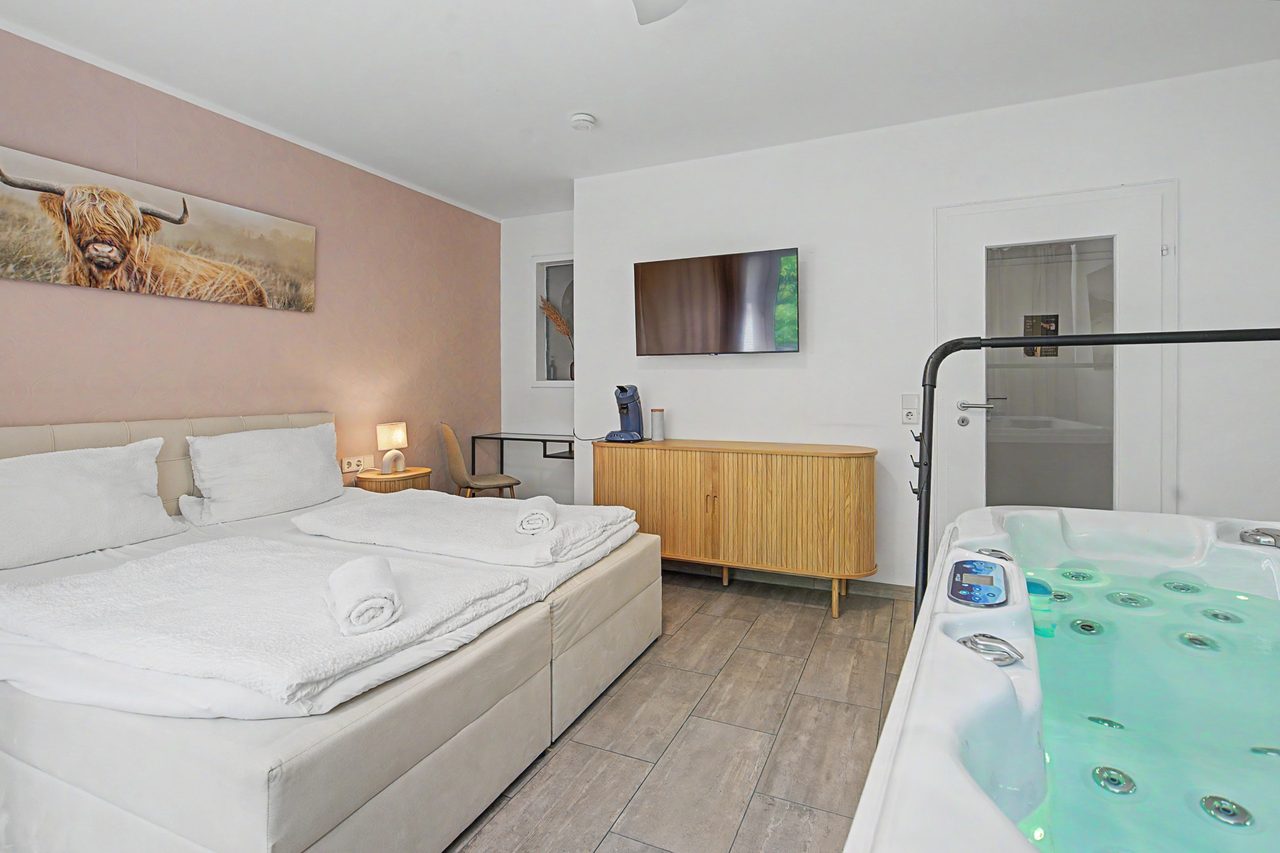 Zimmer mit Doppelbett, Whirlpool und Wandfernseher