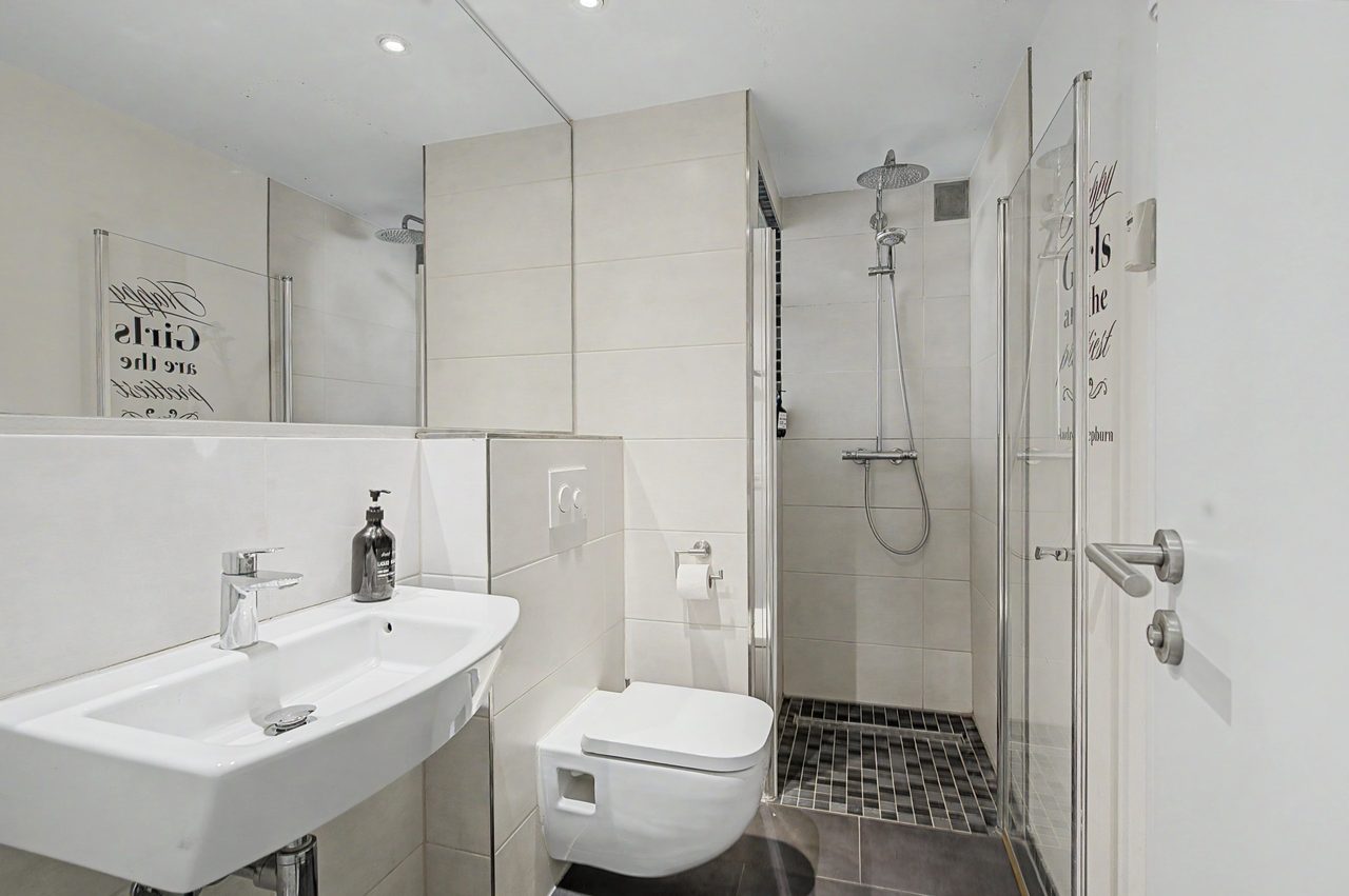 Badezimmer mit Waschbecken, Wand-WC und Dusche mit Glaswand