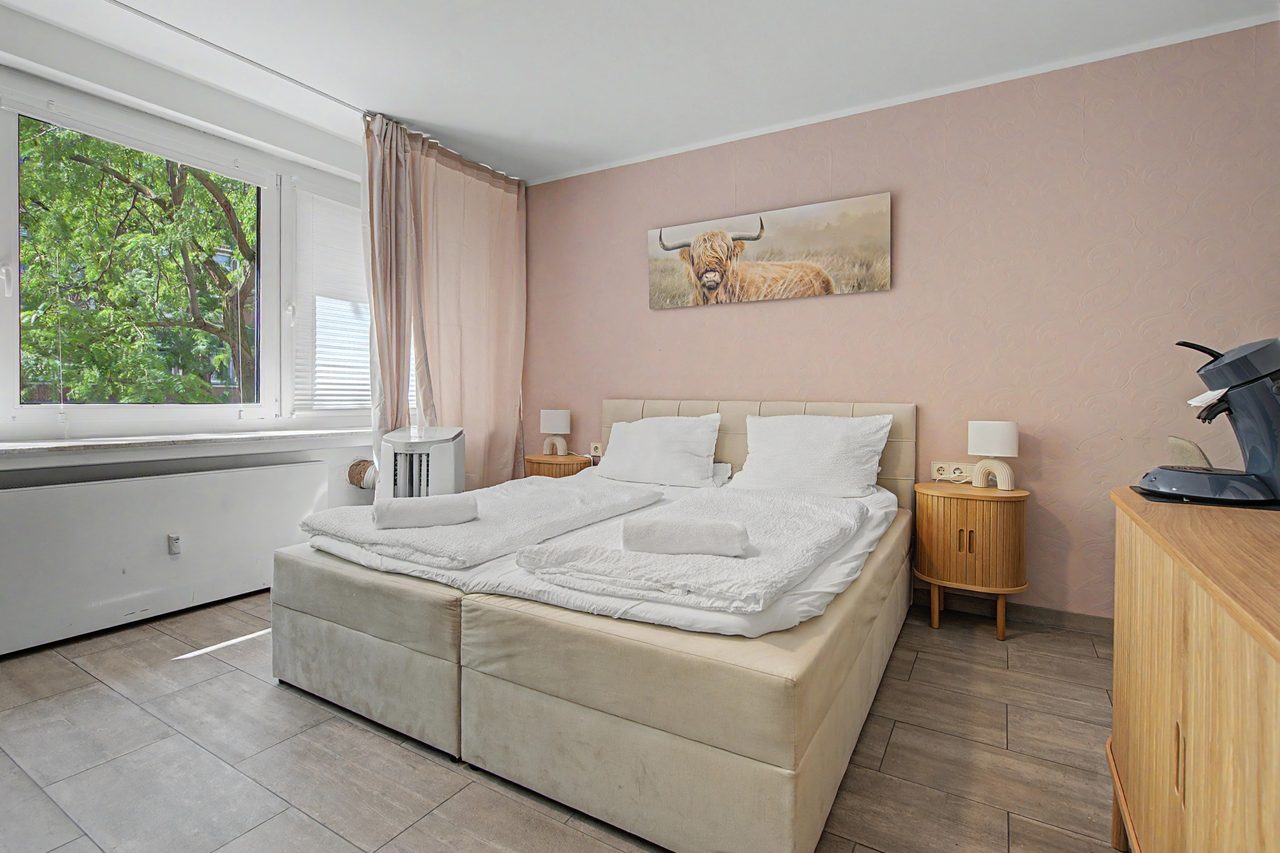 Schlafzimmer mit Doppelbett, Nachttischen und Bild mit Hochlandrind