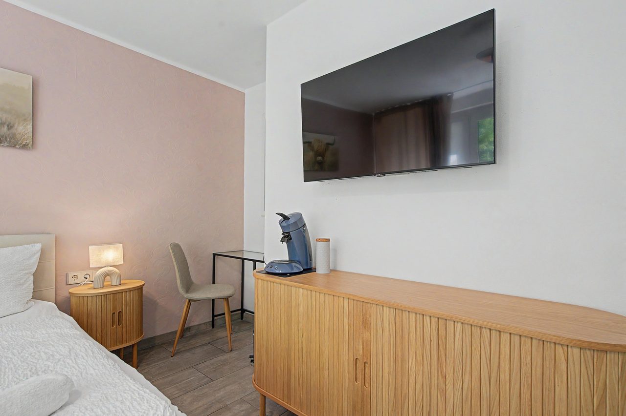 Zimmer mit Wandfernseher, Holzsideboard und Kaffeemaschine