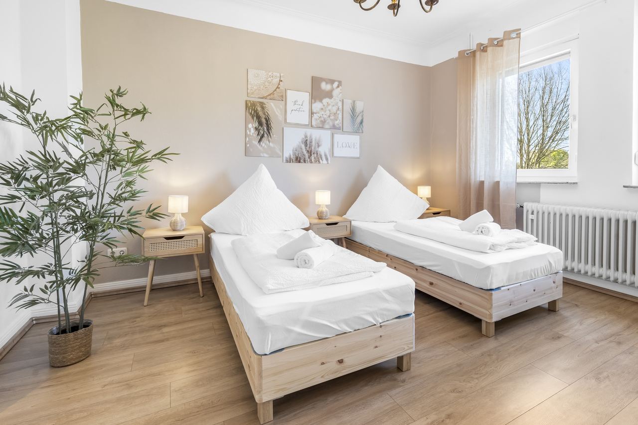 Schlafzimmer mit zwei Einzelbetten aus Holz und Bambuspflanze