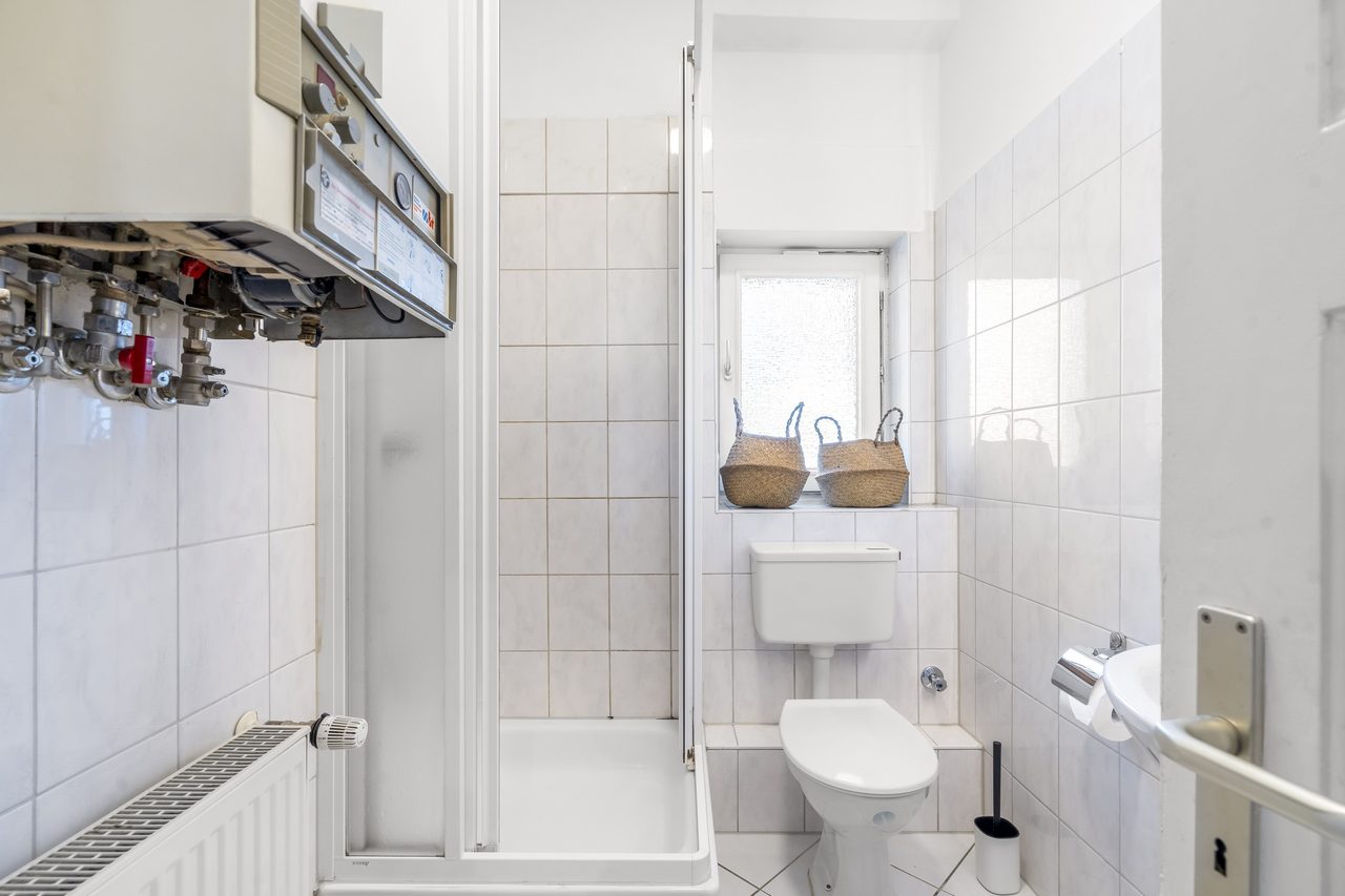 Badezimmer mit Dusche, WC und Therme an der Wand