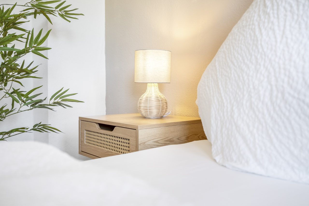 Nachttisch mit Lampe neben Bett mit weißem Kissen