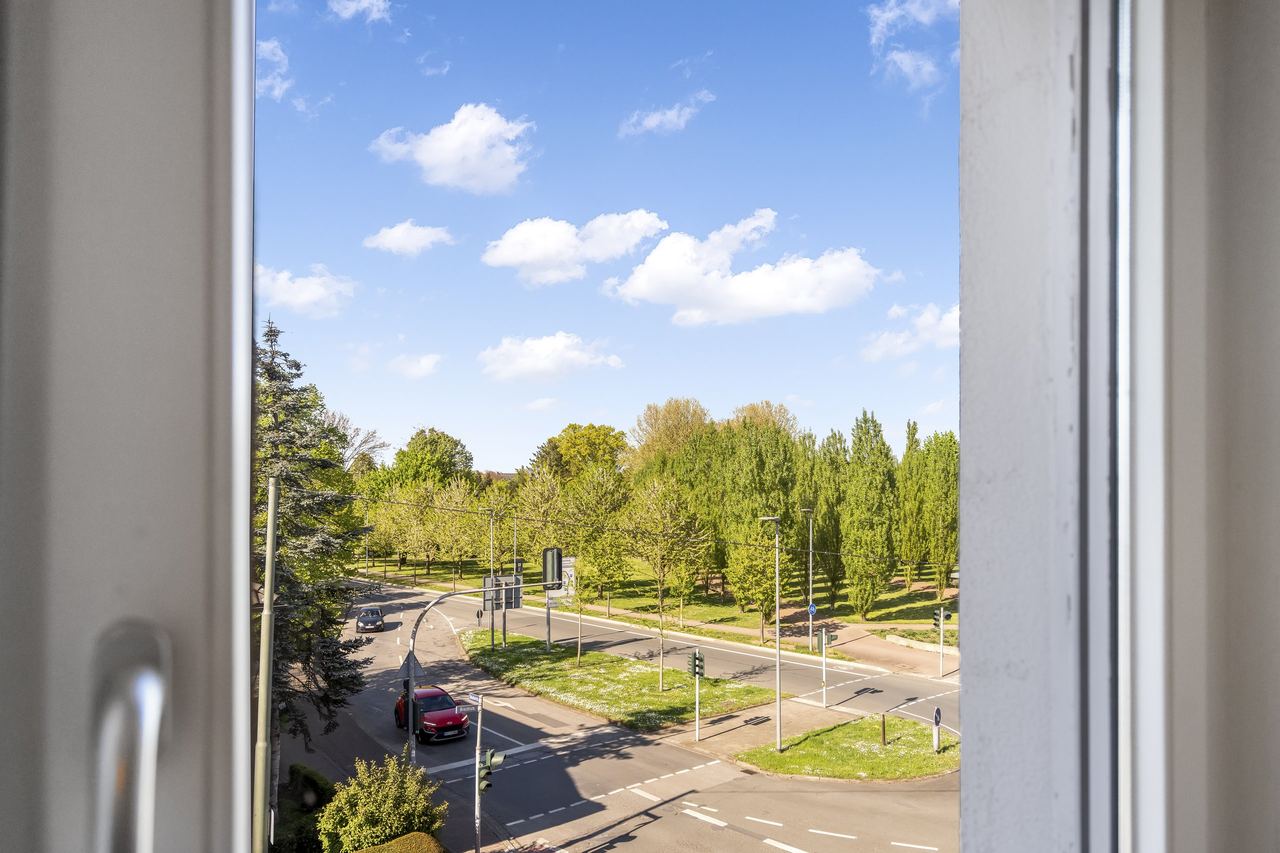 Blick aus dem Fenster auf eine Straßenkreuzung und Bäume