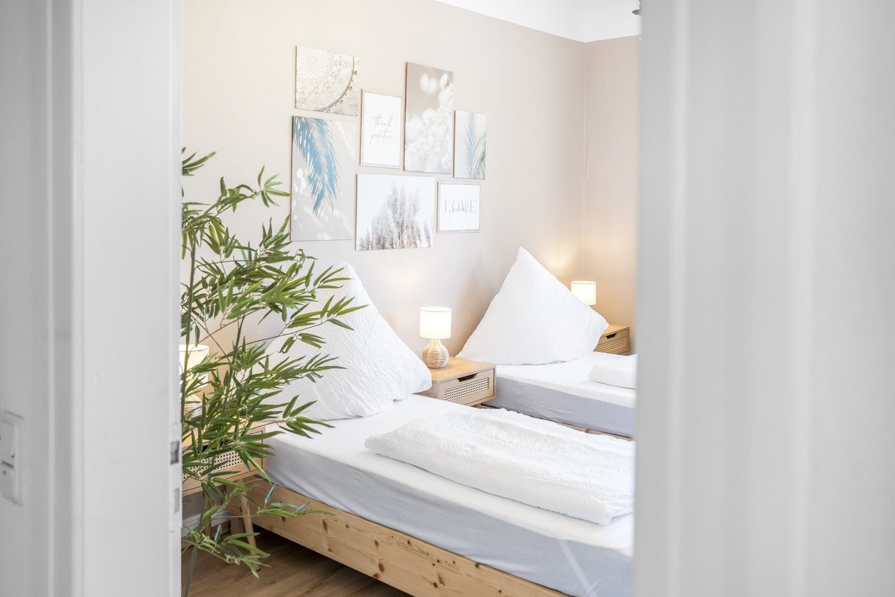 Schlafzimmer mit zwei Einzelbetten, Zimmerpflanze und Bildern an der Wand