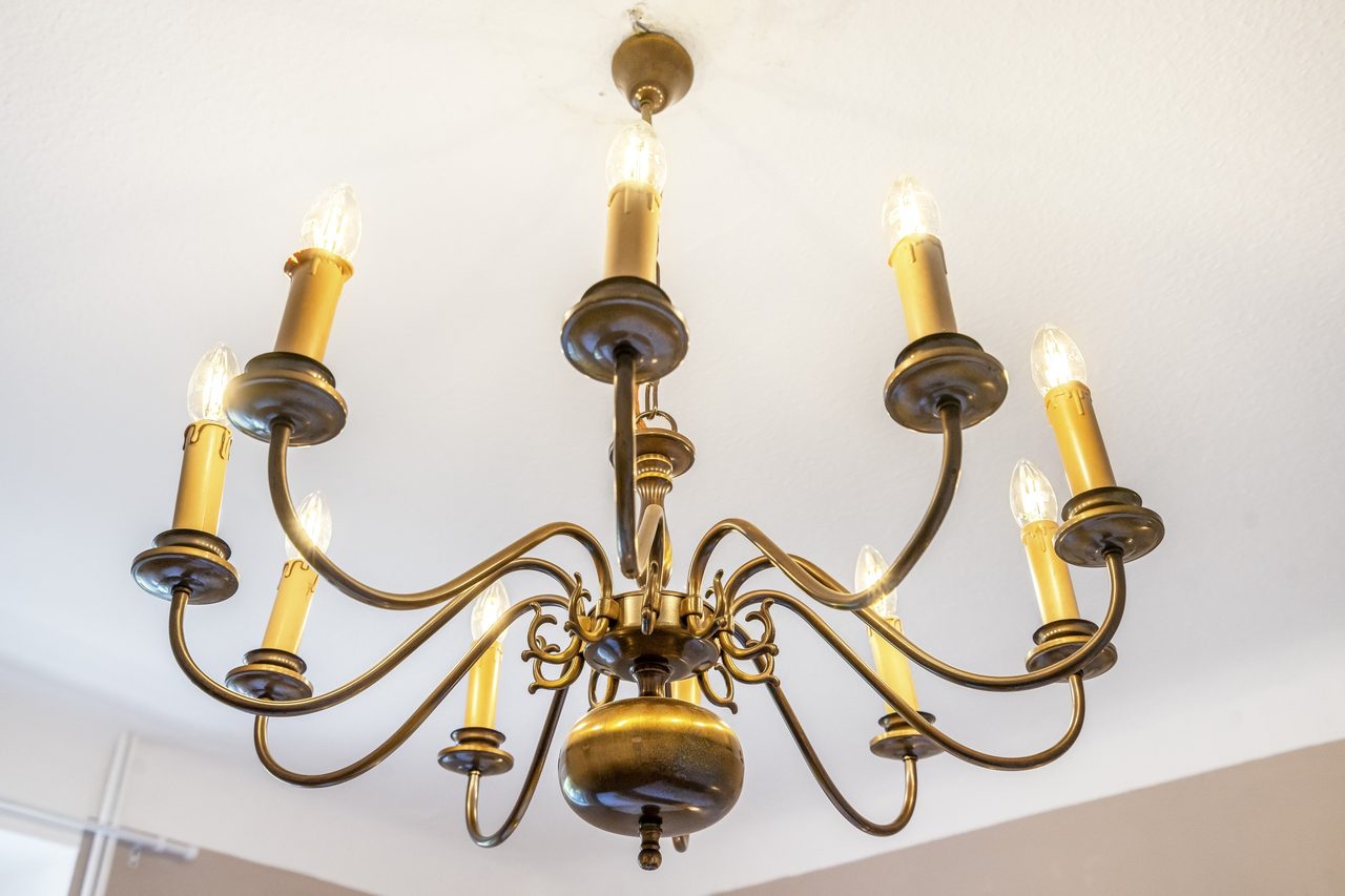 Kronleuchter aus Messing mit Kerzenlampen an weißer Decke