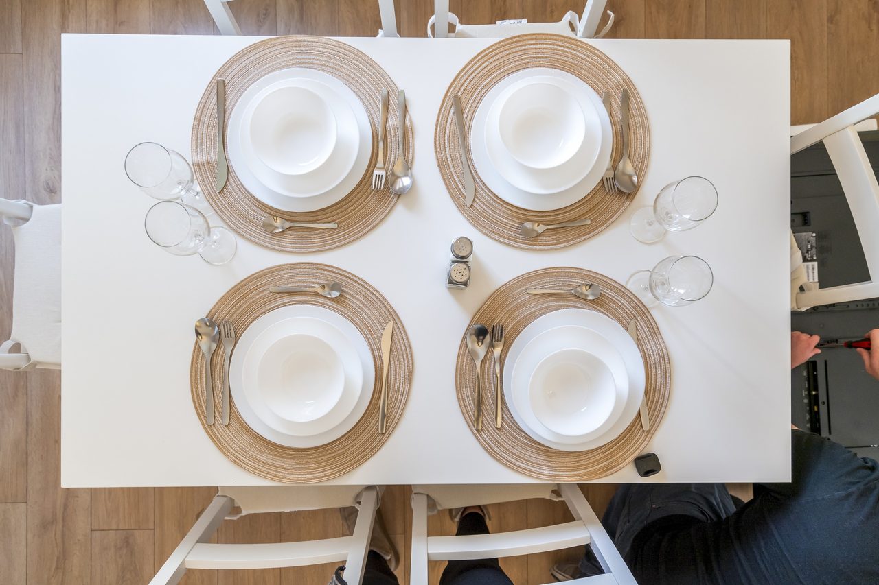 Esstisch von oben mit vier Gedecken, Tischsets und Gläsern