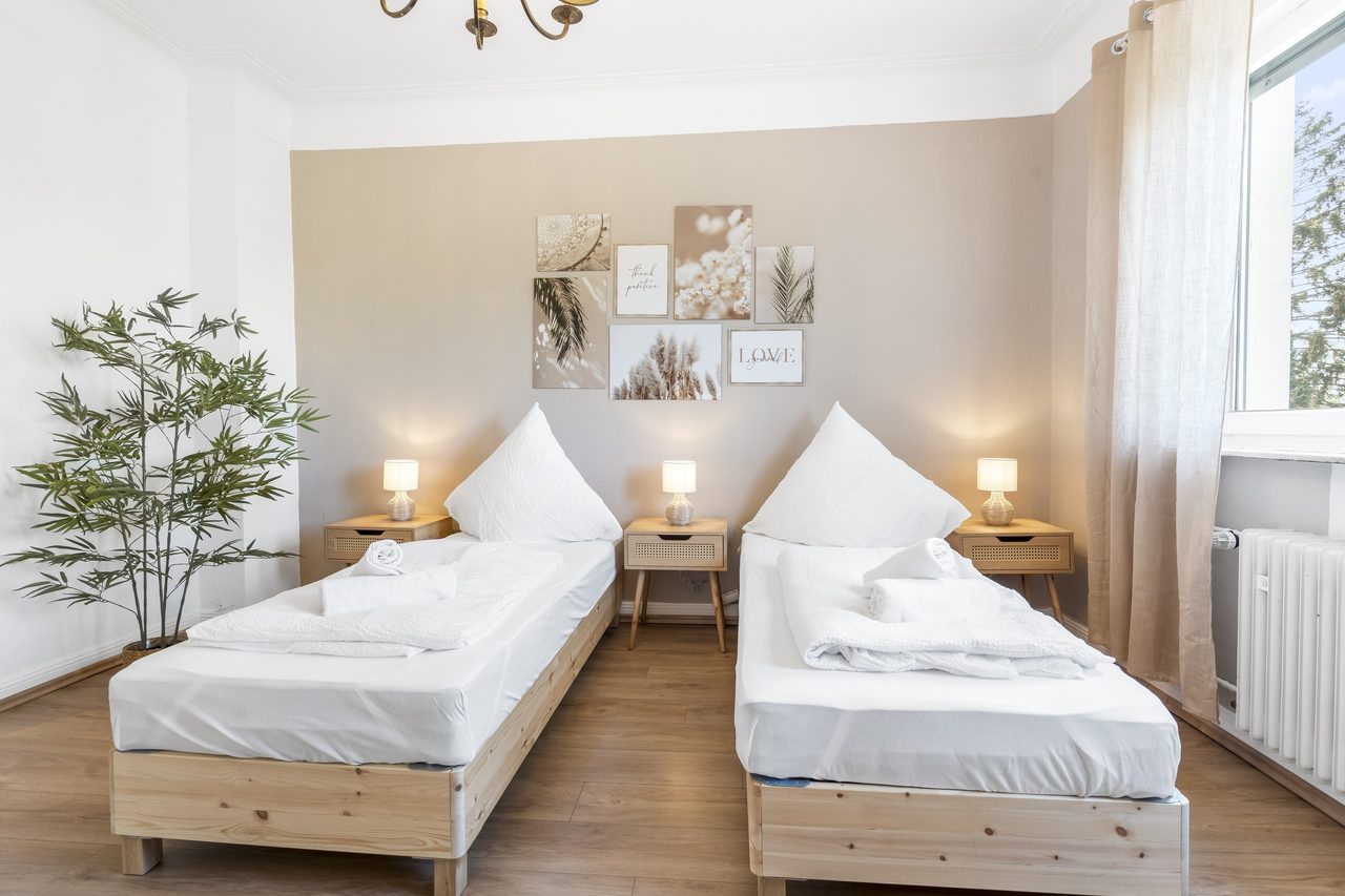Schlafzimmer mit zwei Einzelbetten, Zimmerpflanze und Kronleuchter