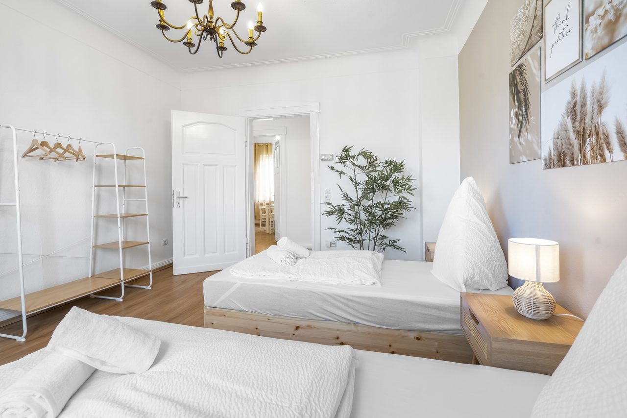 Schlafzimmer mit Einzelbett, offenem Kleiderregal und Nachttischlampe
