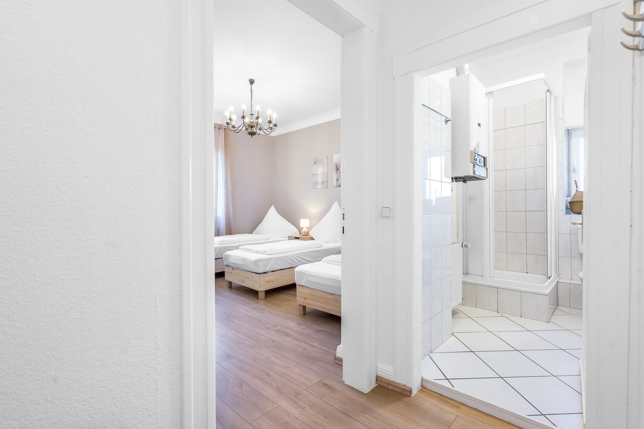 Blick durch die Tür in ein Schlafzimmer mit Einzelbetten und ins Bad