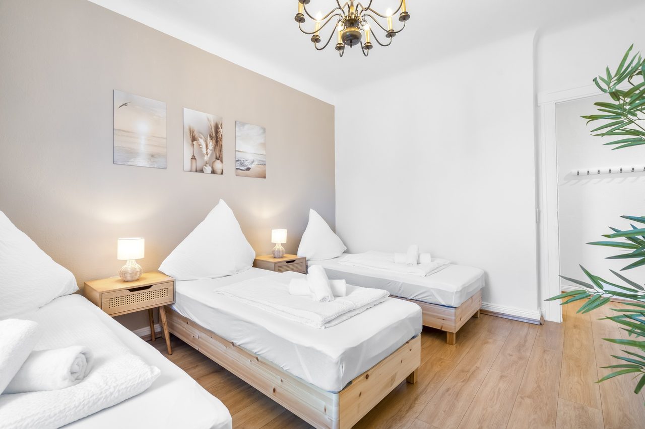 Schlafzimmer mit zwei Einzelbetten, Nachttischlampe und drei Wandbildern