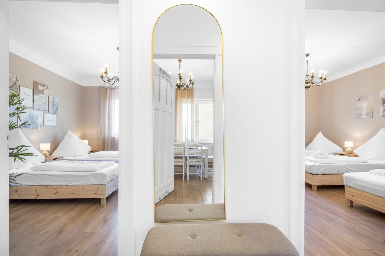 Flur mit Bogenspiegel und Blick in zwei Schlafzimmer mit Einzelbetten
