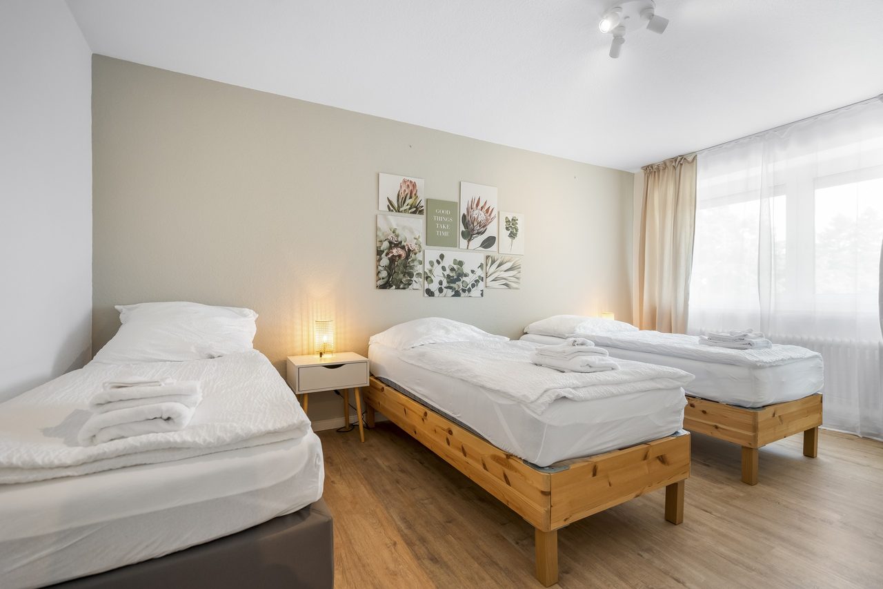 Schlafzimmer mit drei Einzelbetten aus Holz und Handtüchern