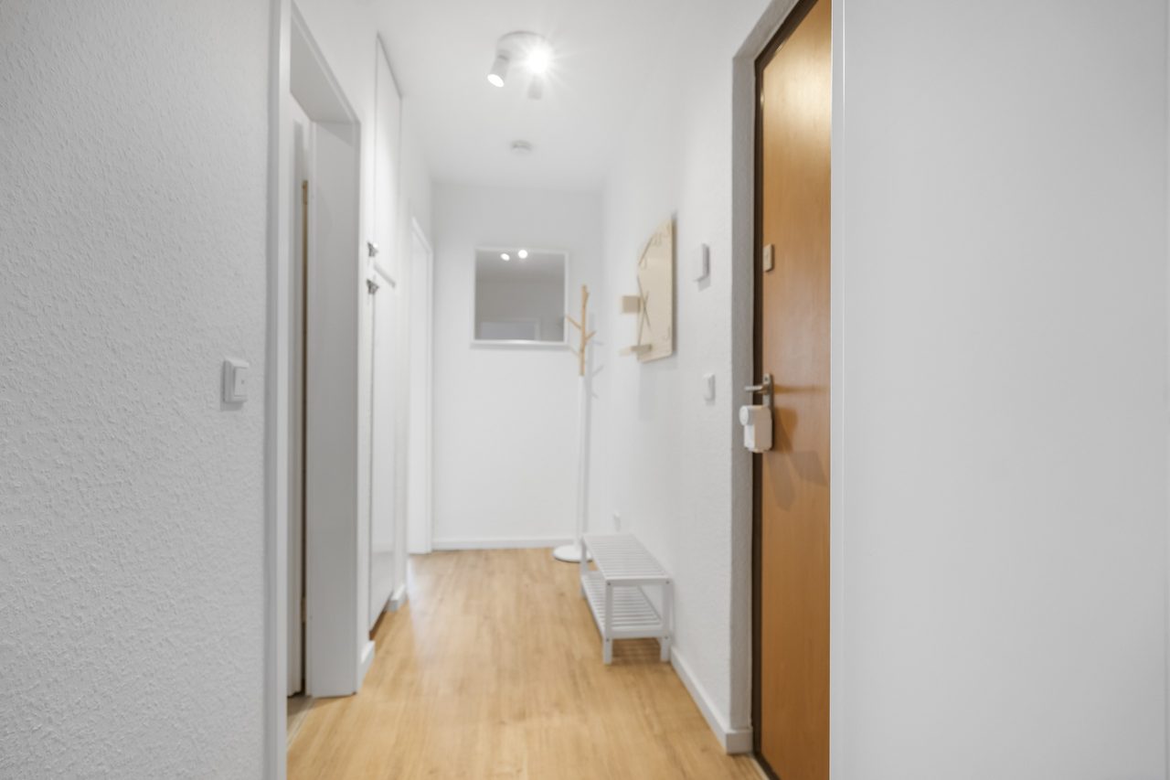 Flur mit Holzboden, weißen Wänden und Wohnungstür
